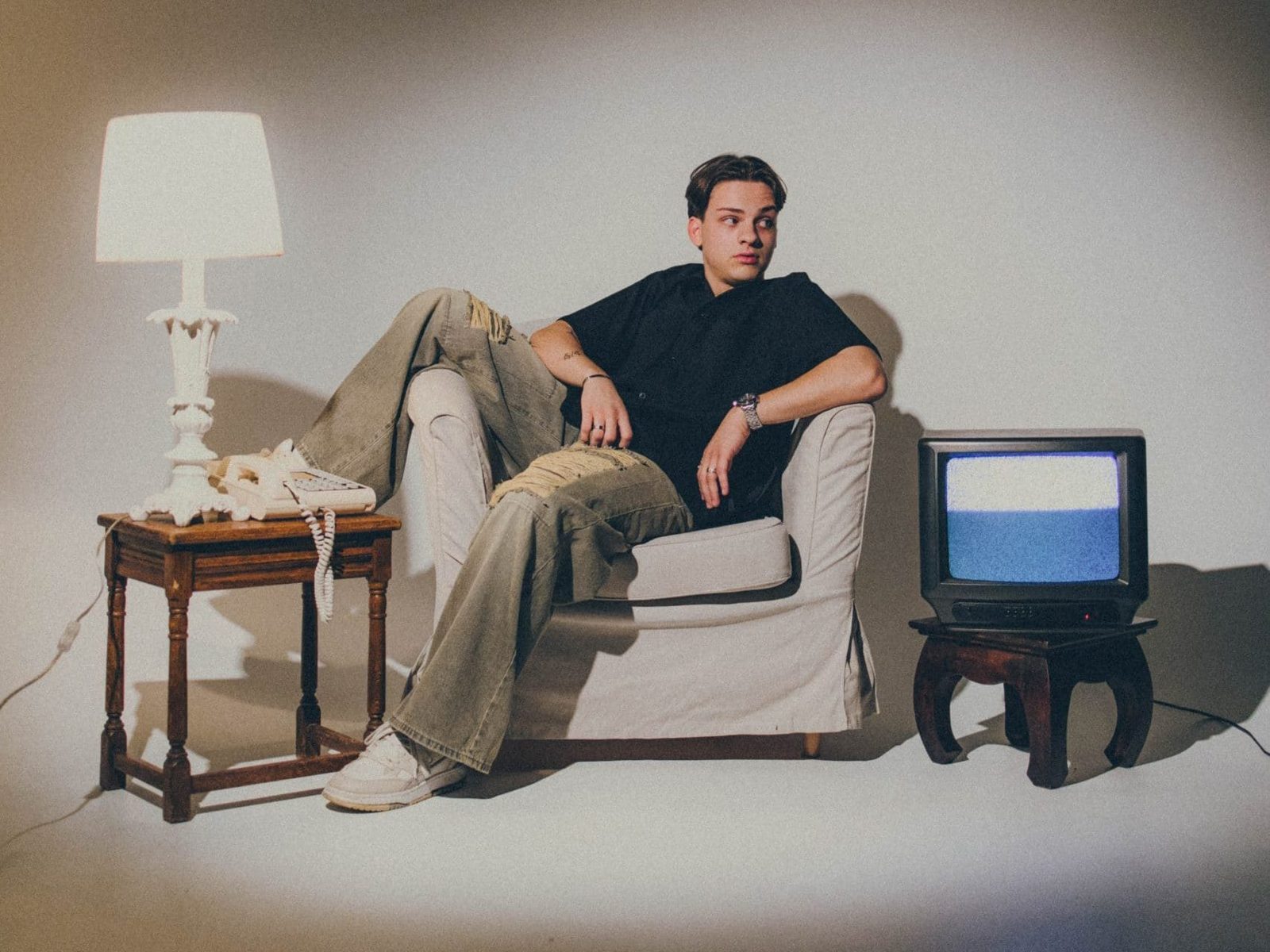 NYCO relaxed in an armchair between an old lamp and a vintage TV