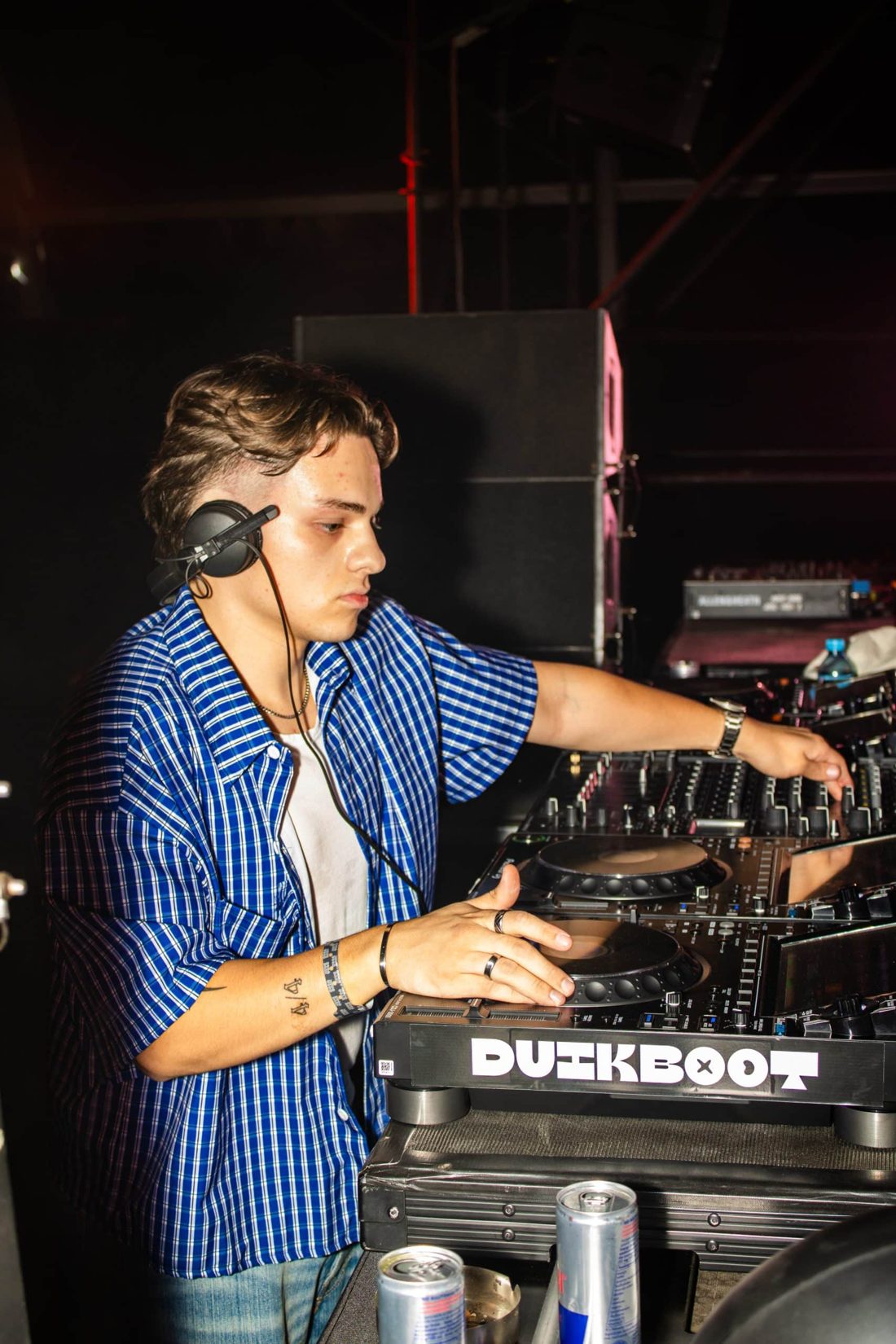 NYCO behind the decks, headphones on one ear